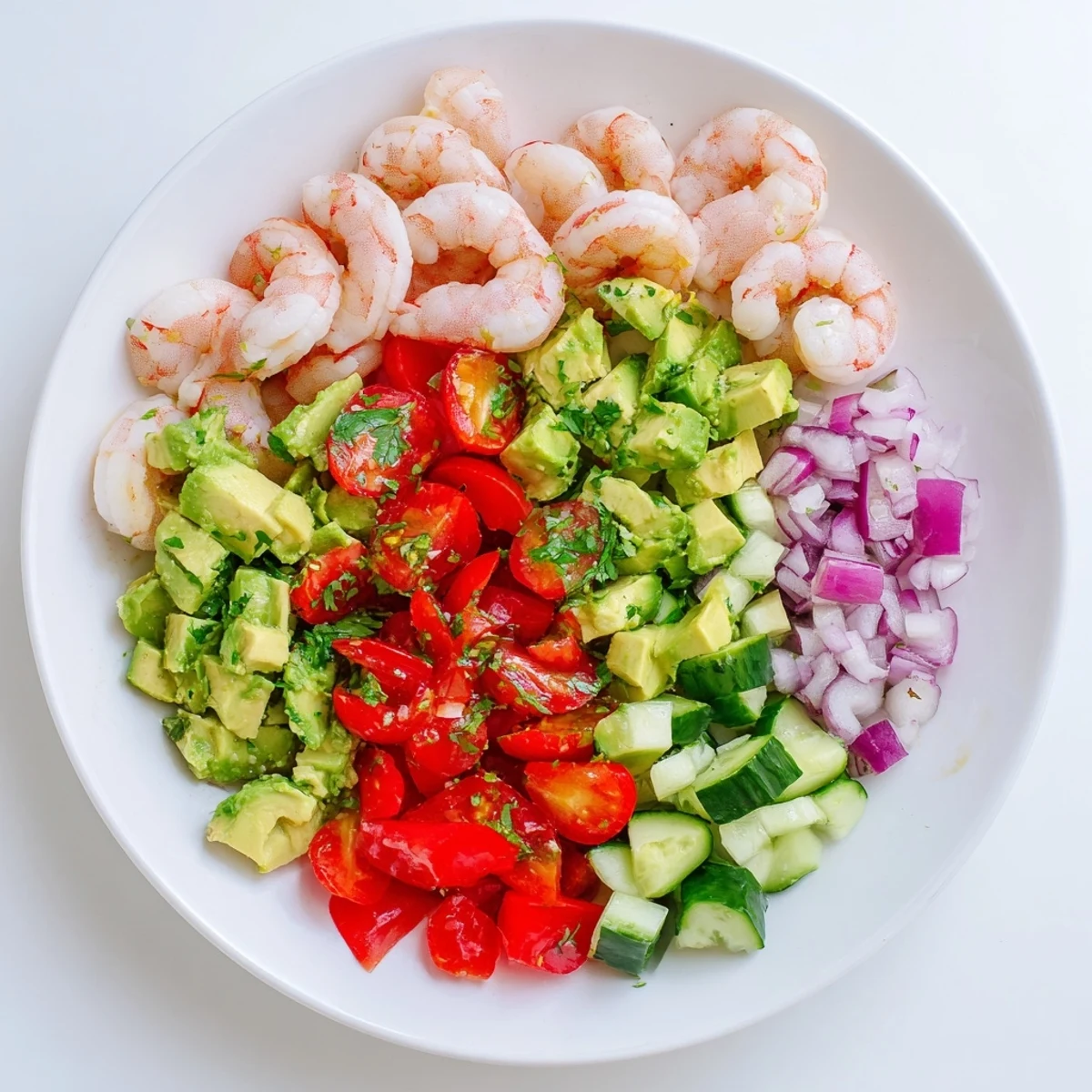 Vibrant healthy shrimp avocado salad served in a white bowl with diced crisp vegetables and cilantro garnish