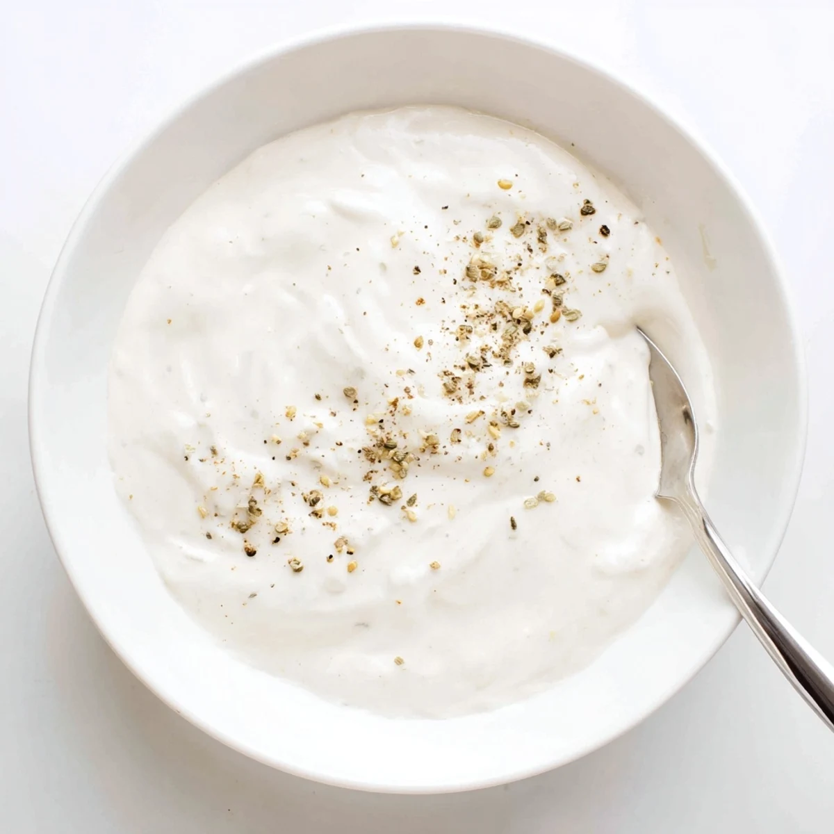 Creamy white Easy Chicken Shawarma garlic sauce drizzled over spiced grilled chicken slices in a bowl