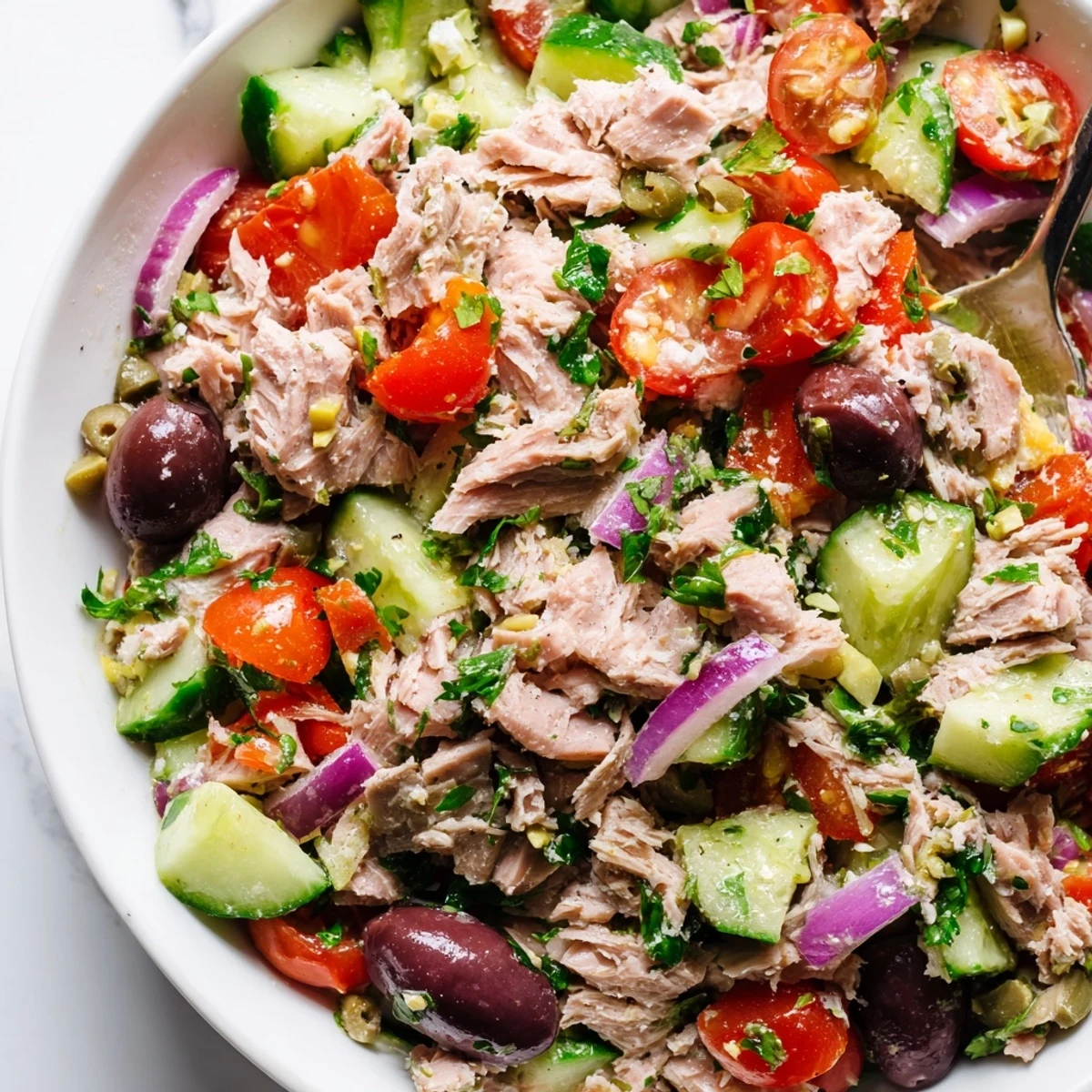 Bright Mediterranean tuna salad with juicy tomatoes, olives, and crisp cucumber on a rustic plate