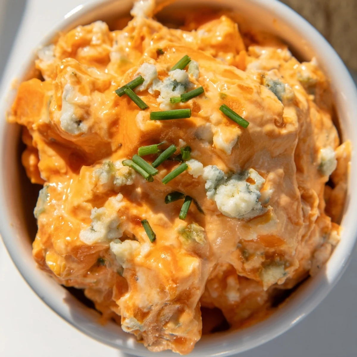 Creamy buffalo pickle dip served in a bowl with crisp celery sticks and tortilla chips