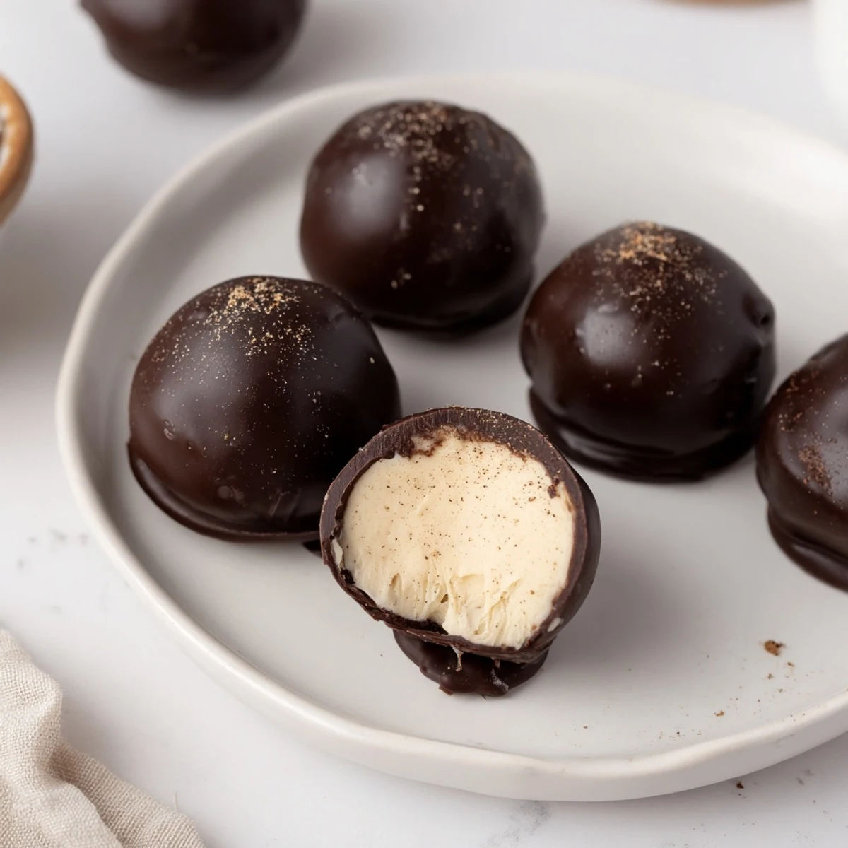 Plated Dark Chocolate Eggnog Truffles, creamy centers revealed beside coffee mug