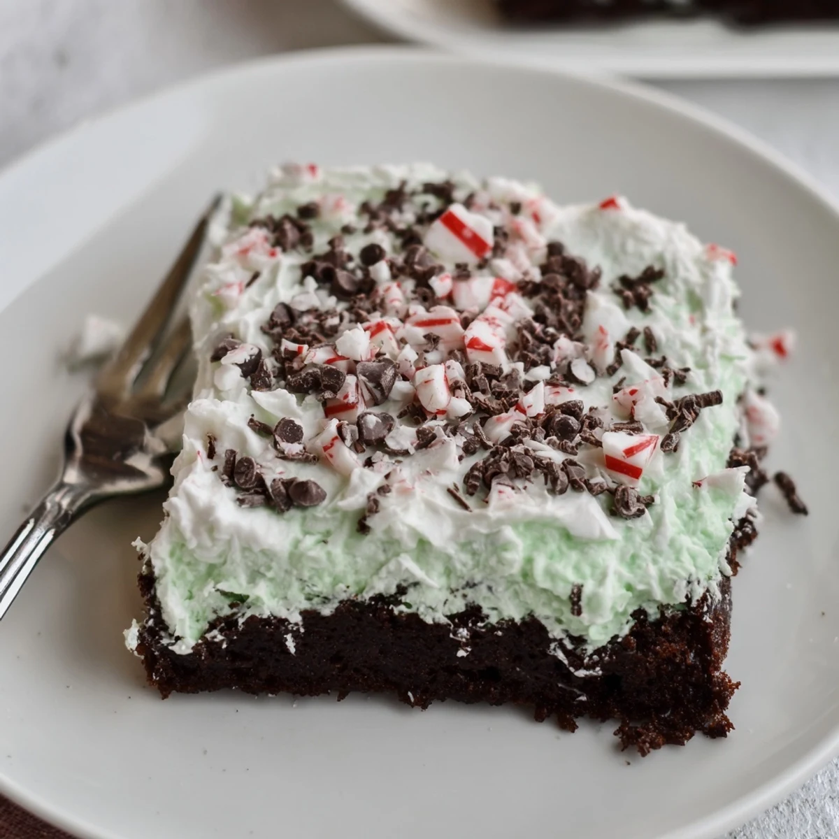 Slice of Peppermint Poke Cake revealing minty pudding pooled in holes