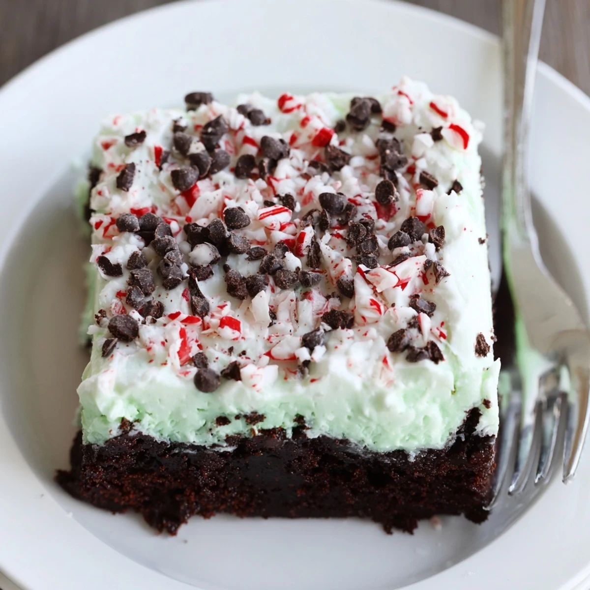 Peppermint Poke Cake chilled on festive plate, topped with chocolate shavings