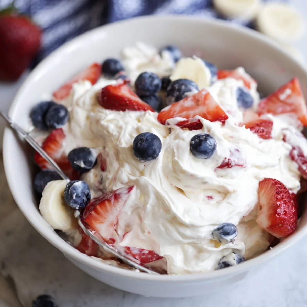 Red White And Blue Cheesecake Salad piled with glossy berries and creamy swirls