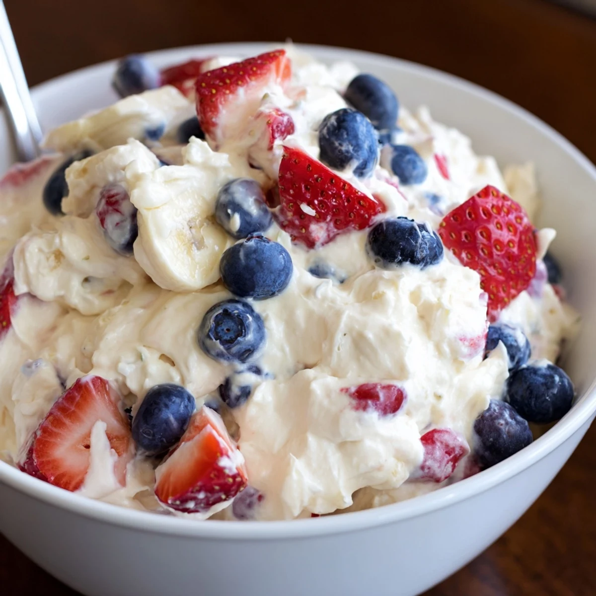 Chilled Red White And Blue Cheesecake Salad with sliced bananas and bright strawberries
