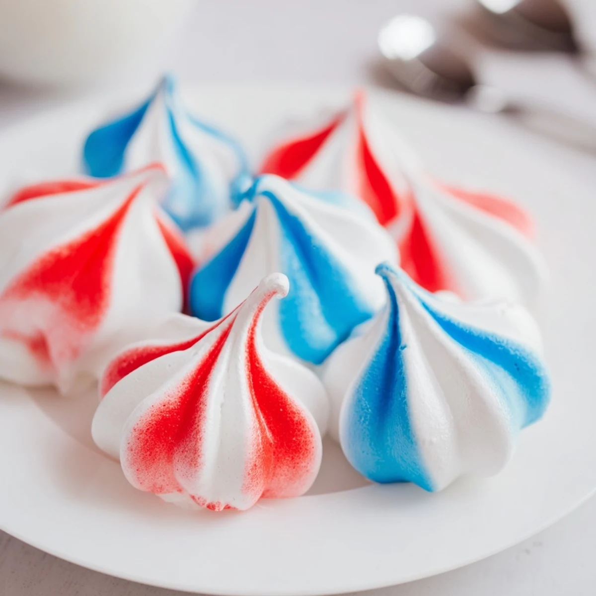 A pile of Patriotic Meringue Kisses on a tray, airy and crunchy