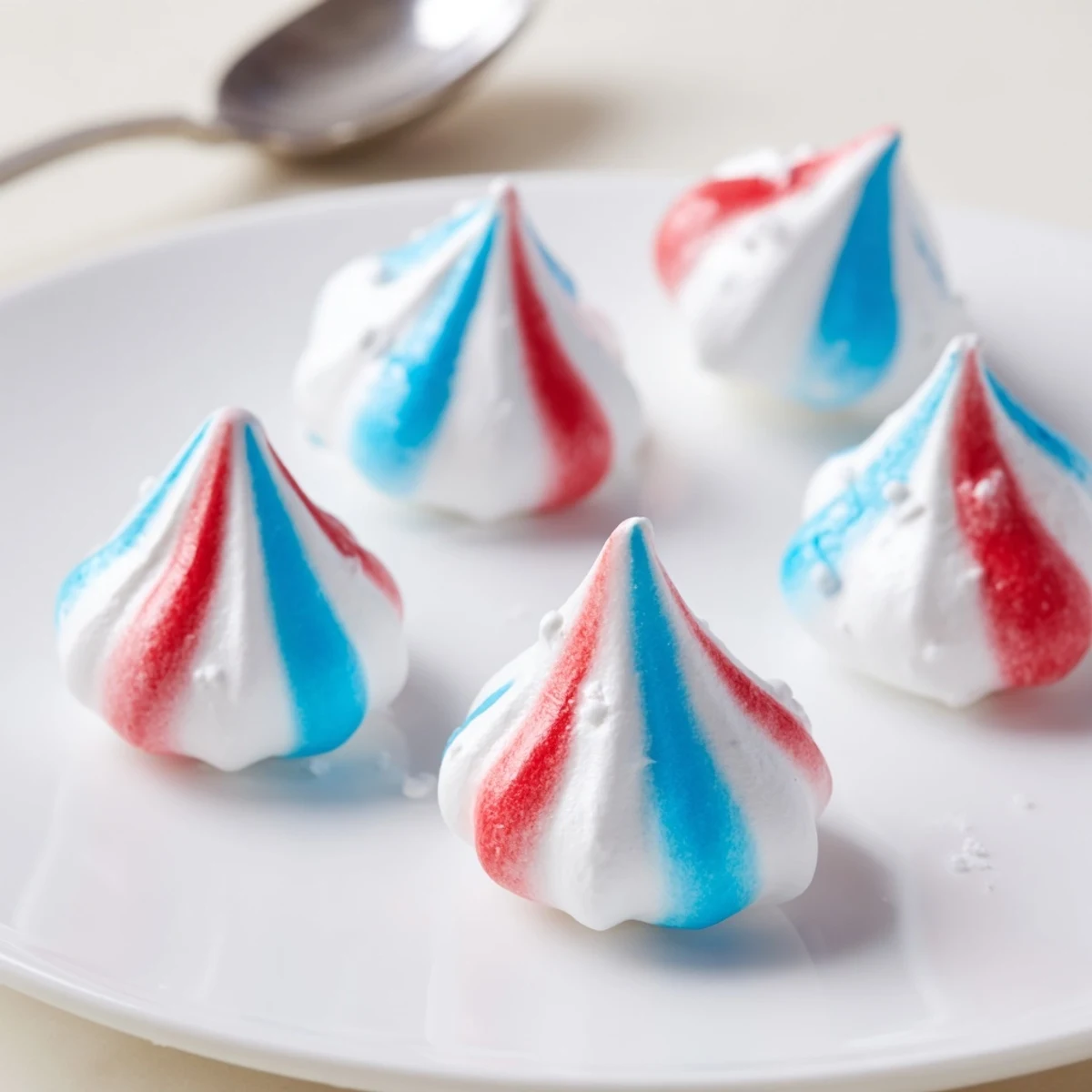 Patriotic Meringue Kisses: delicate red, white, blue swirls cooling on parchment