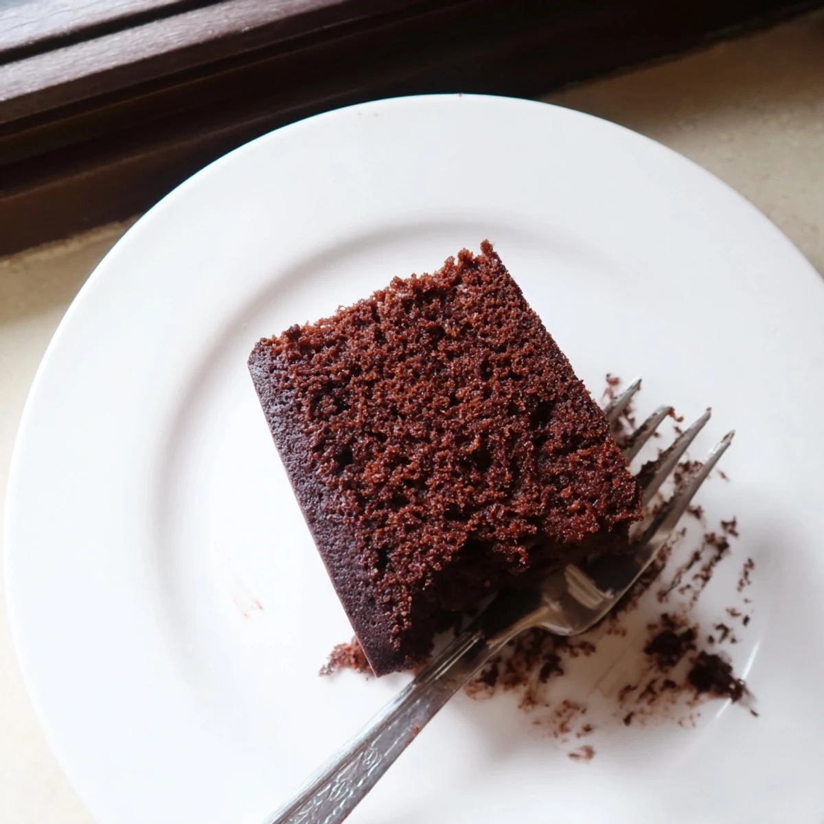 Two layer chocolate cake with mayonnaise frosted with rich chocolate buttercream on white serving plate