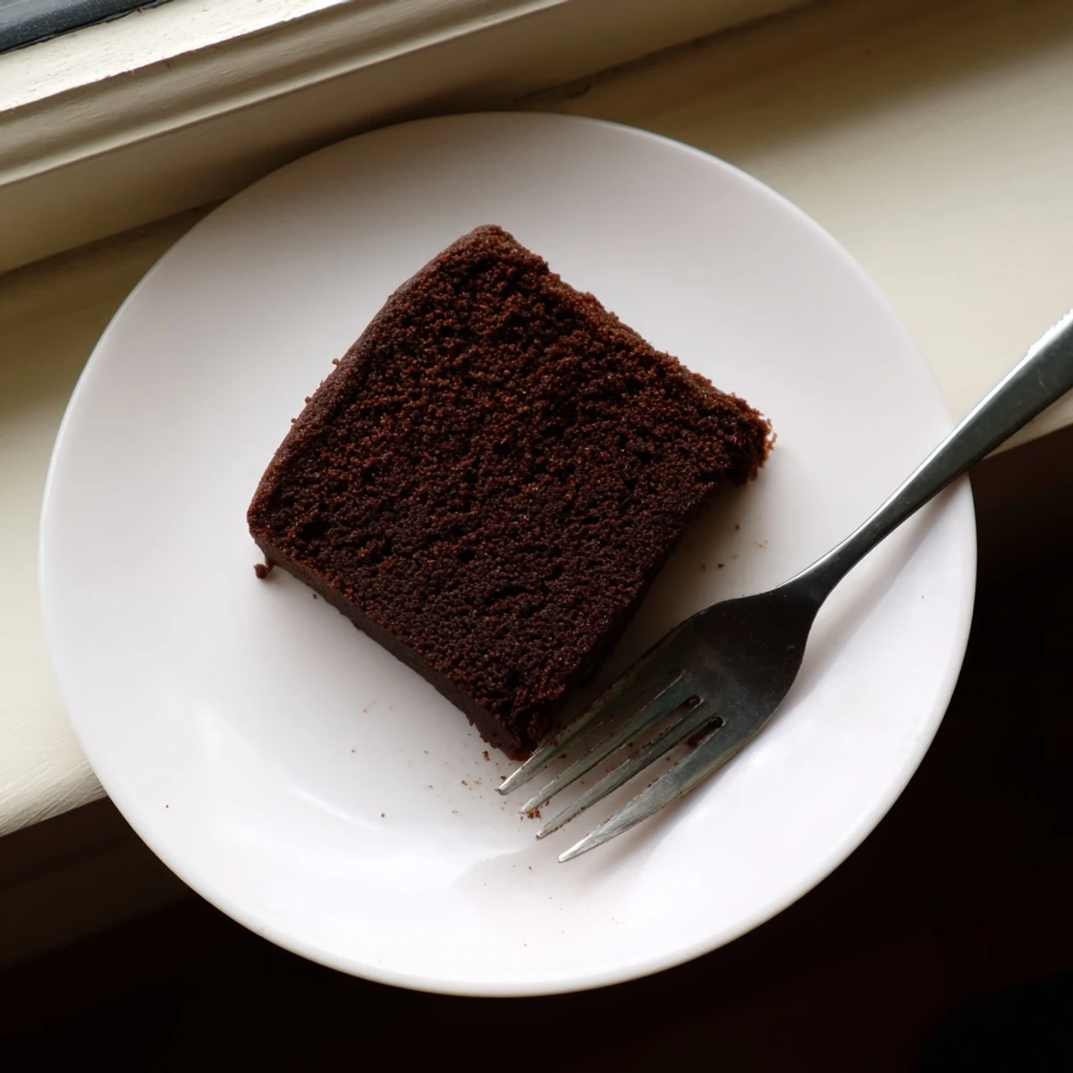 Homemade chocolate cake with mayonnaise recipe showing exceptionally moist slices on decorative cake stand