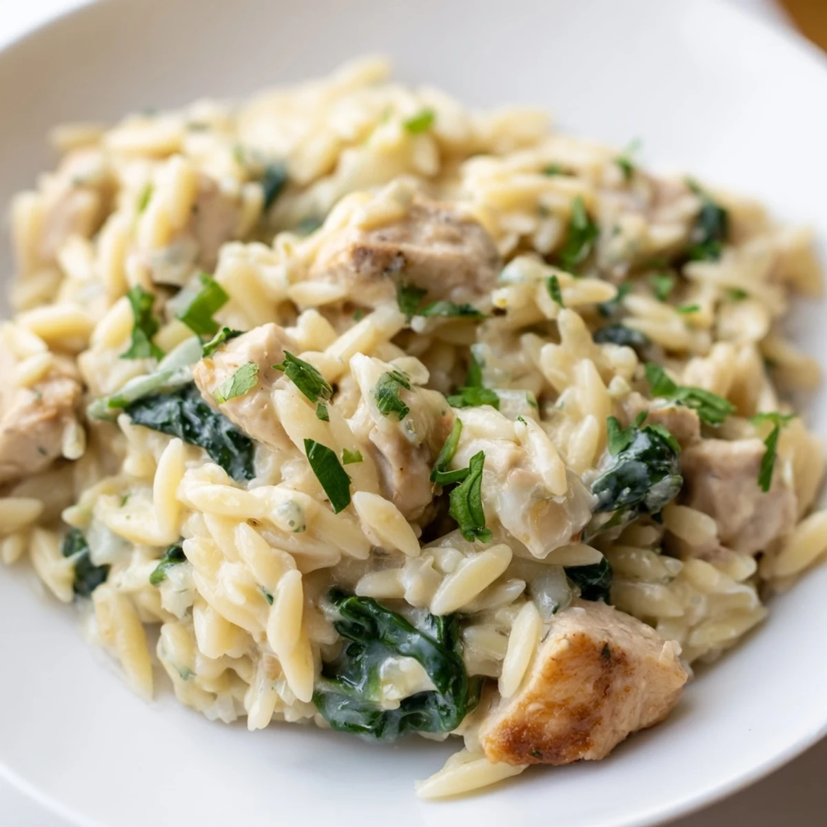 Single skillet comfort meal featuring seasoned chicken, orzo, and vibrant green spinach leaves
