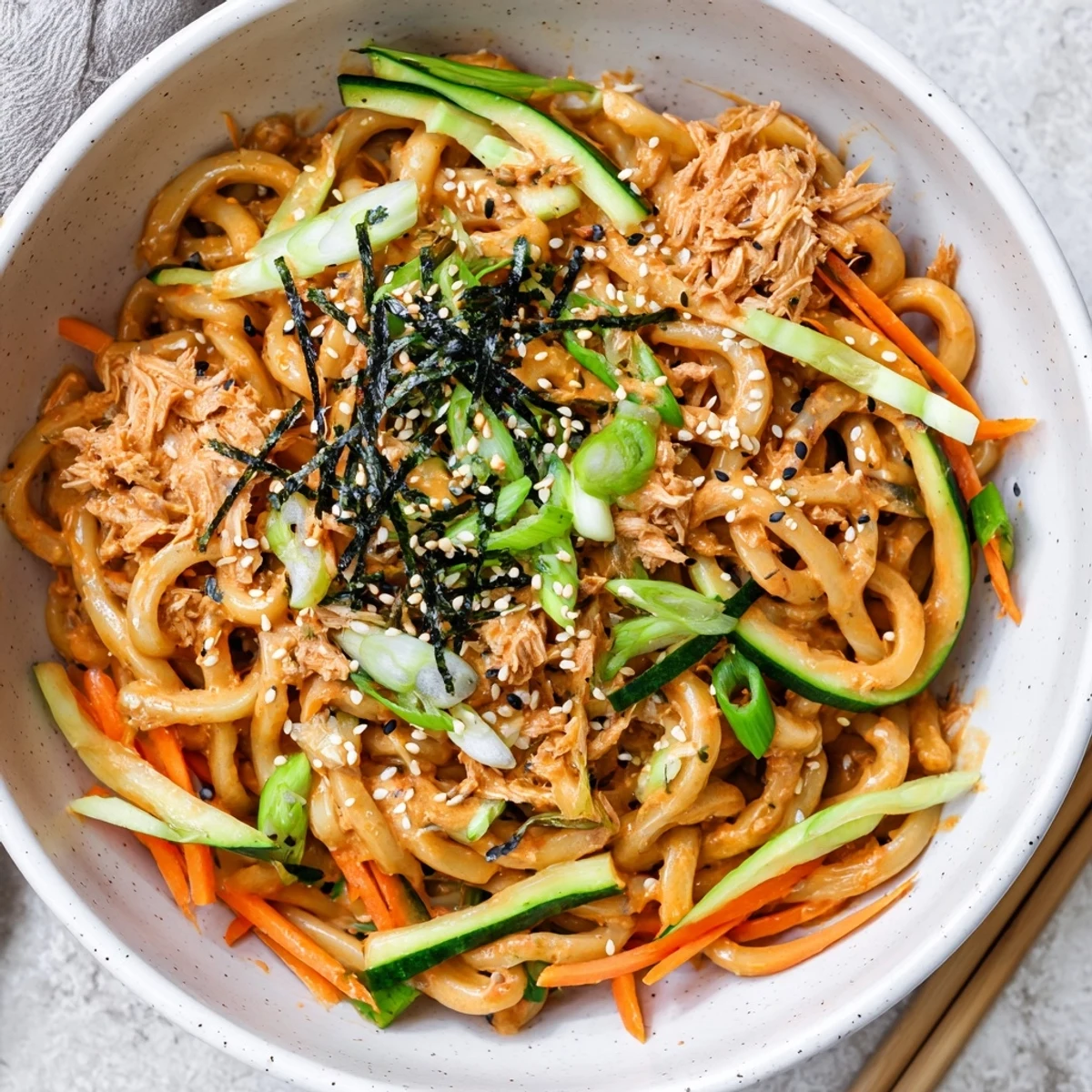 Spicy Tuna Udon noodles coated in creamy sriracha sauce with fresh cucumber and carrot slices