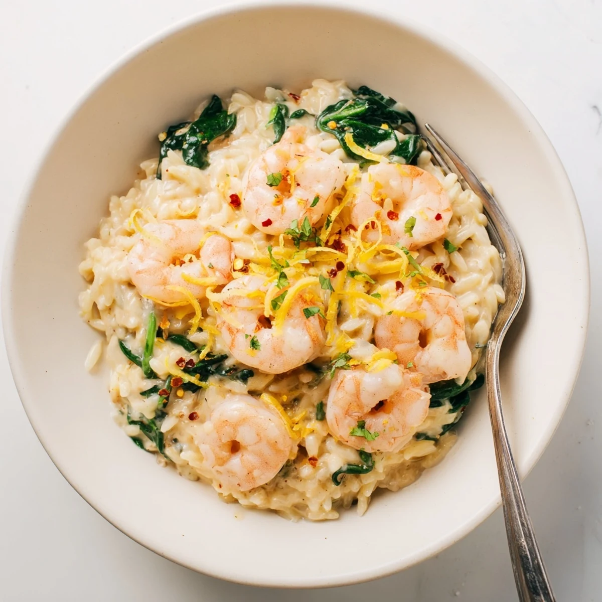 A bowl of Creamy Shrimp Orzo Recipe garnished with parsley and lemon